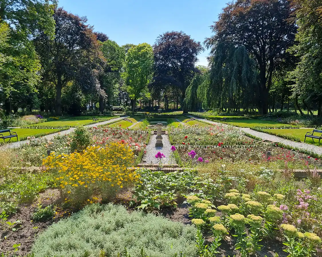 http://Aangelegde%20tuin%20bij%20erfgoed%20met%20kleurrijke%20bloemen%20en%20bomen%20op%20de%20achtergrond