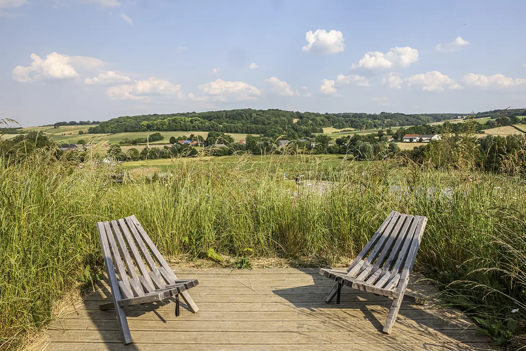 http://Houten%20vlonder%20met%20twee%20stoelen%20uitkijkend%20op%20een%20veld%20met%20heuvels
